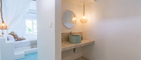 Un baño con un espejo redondo, un lavamanos y una ducha.