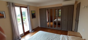 Quarto com cama, guarda-roupa e porta de correr para uma varanda.