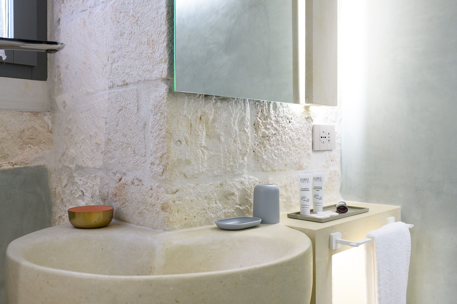 A bathroom with a large sink, a mirror, and a towel rack.