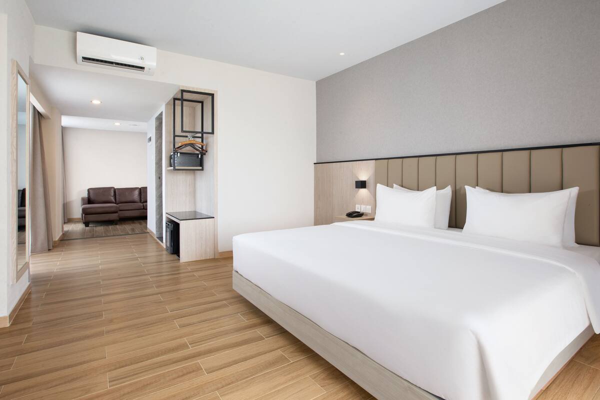 A modern hotel room with a large bed, a sofa, and a small table.