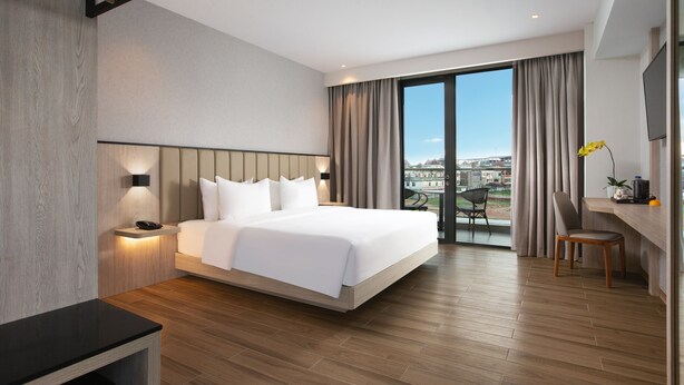 Una habitación de hotel moderna con una cama grande, un escritorio y vistas a la ciudad.