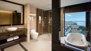 Un baño moderno con un espejo grande, un lavamanos, un inodoro, una ducha y una bañera con vistas al mar.