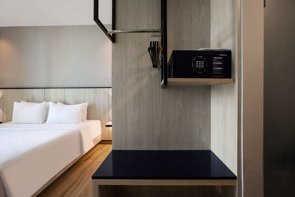 Una habitación de hotel moderna con una cama, una encimera negra y un microondas en la pared.