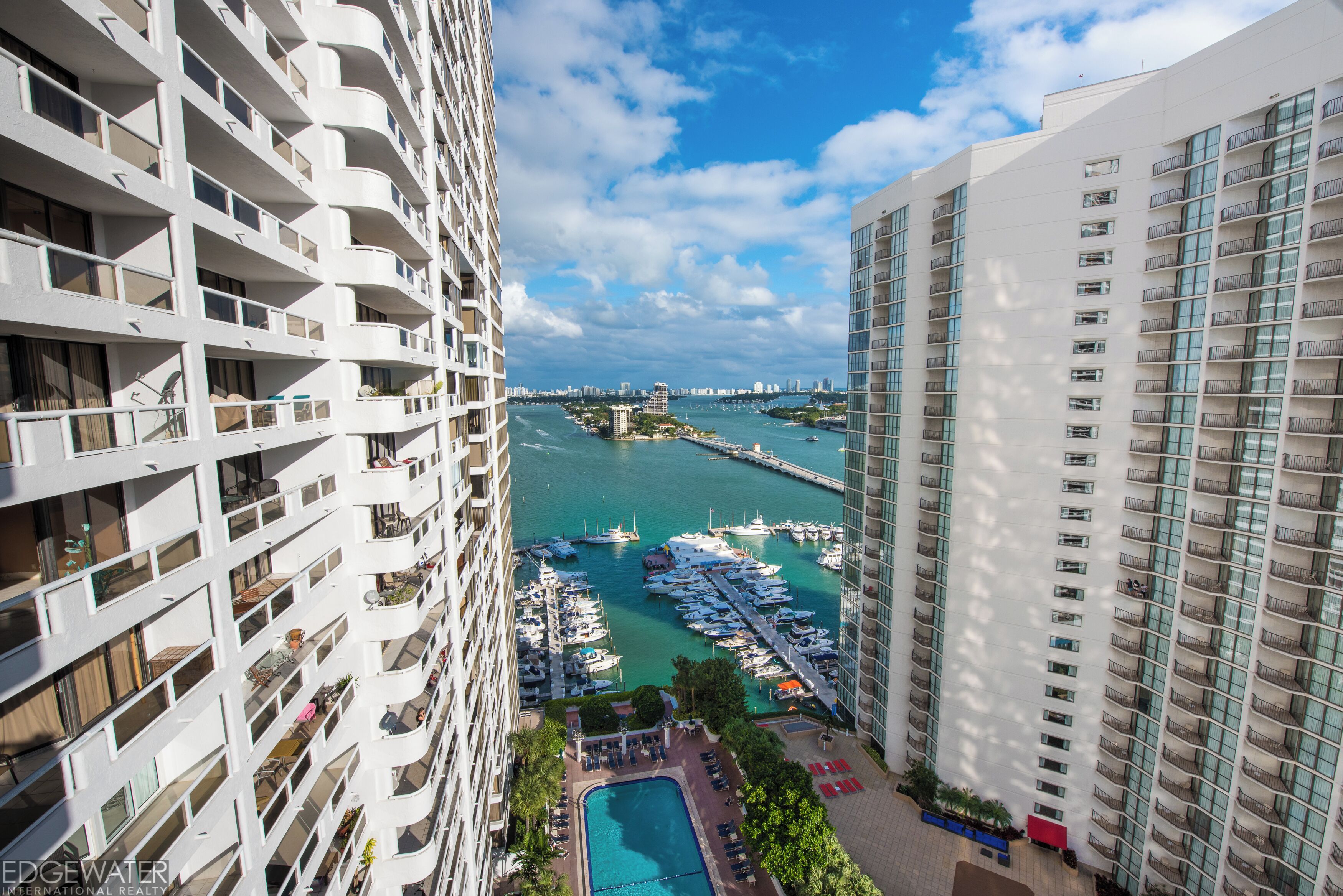 Un immeuble de grande hauteur doté de balcons donnant sur une marina où sont amarrés des bateaux.