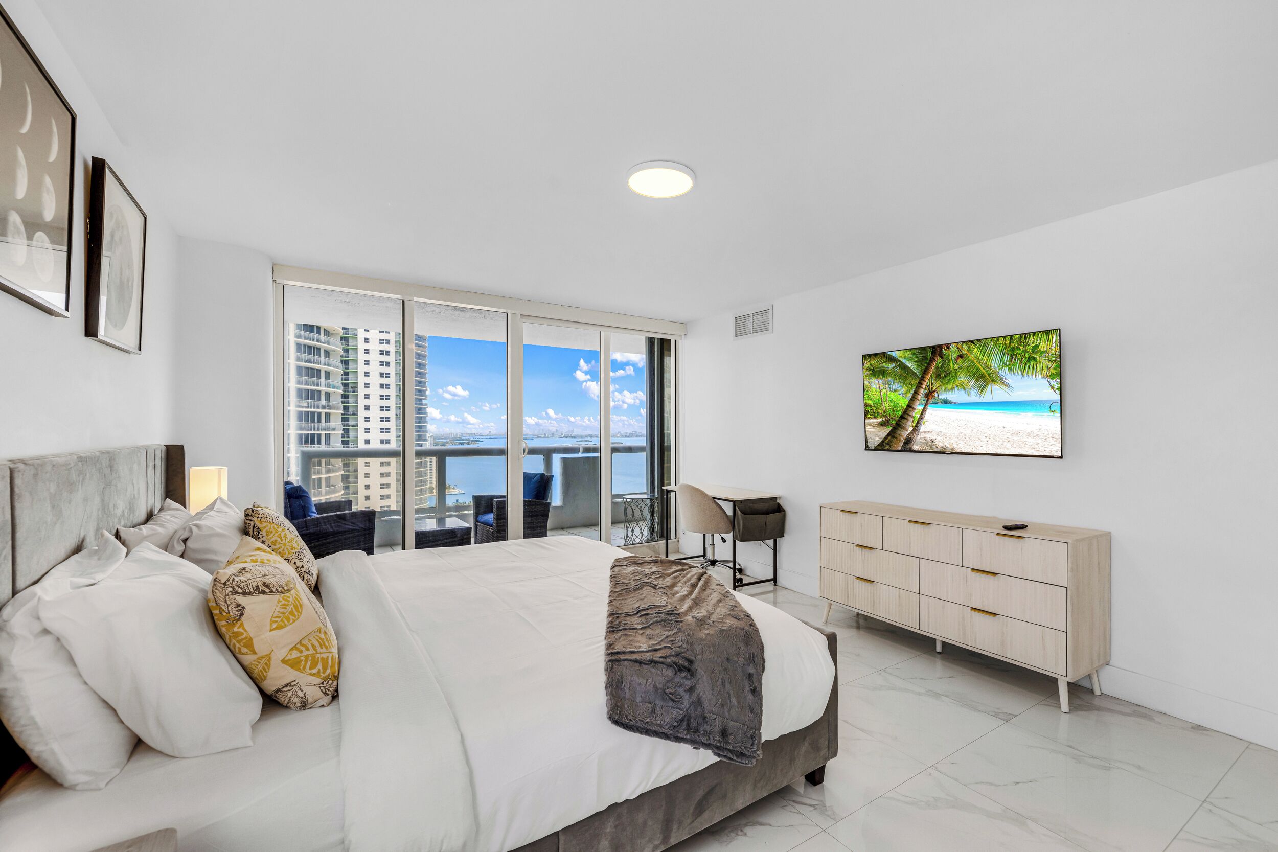 Una habitación de hotel moderna con una cama grande, un escritorio, un televisor y vistas a la ciudad.