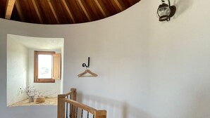 A bedroom with a wooden ceiling, a wooden staircase, a bed, a window, and a wall-mounted light fixture. - Beautiful mill and views, in the hinterland of the Algarve coast line.<br> (Alcantarilha)