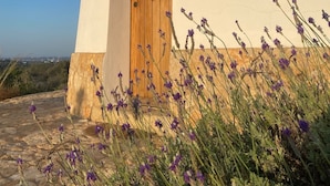 A building with a wooden door and a wall-mounted light fixture. - Beautiful mill and views, in the hinterland of the Algarve coast line.<br> (Alcantarilha)
