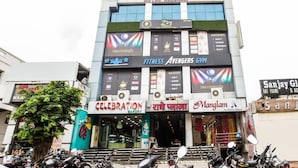 A multi-story building with various businesses including a gym, bakery, and a hotel. - Mgh 114 Hotel Krishna Udaipur (Udaipur)