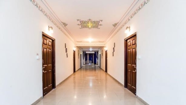 A hallway with two doors on each side, a tiled floor, and a decorative ceiling. - Mgh 114 Hotel Krishna Udaipur (Udaipur)