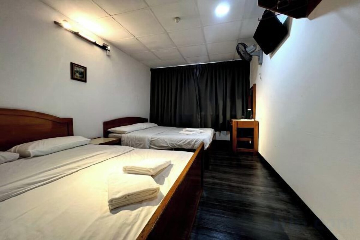 A hotel room with two beds, a desk, and a television.