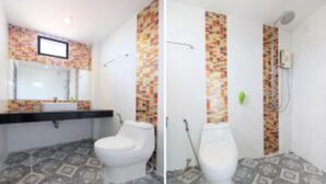 Een badkamer met betegelde vloer, toilet, wastafel en douche.