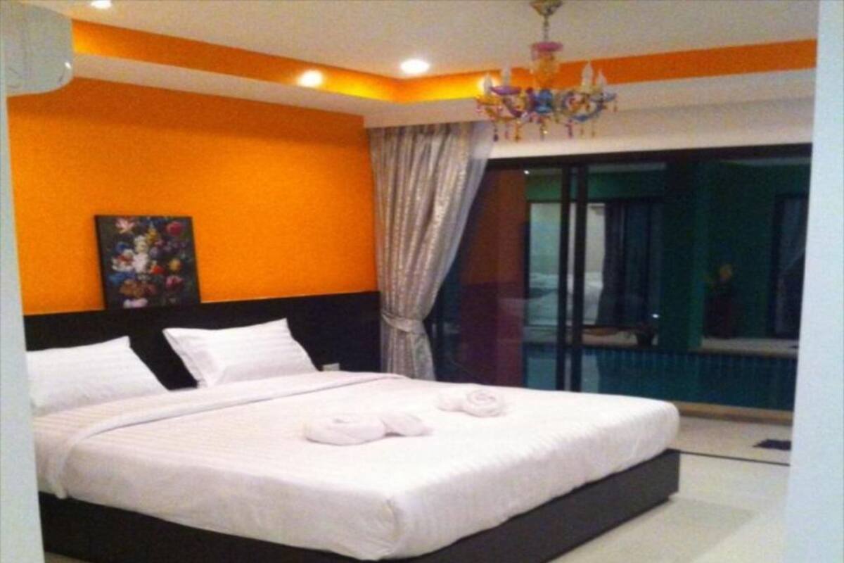 Un dormitorio de hotel moderno con una cama grande, una araña y vistas al exterior.