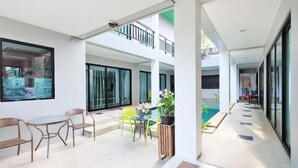 Een moderne, open woonkamer met een glazen balustrade, rieten meubels en een potplant.