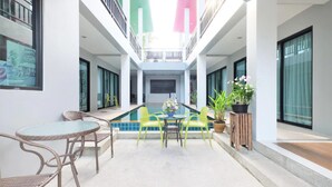Een modern binnenzwembad met een glazen tafel en stoelen, omringd door witte muren en grote ramen.