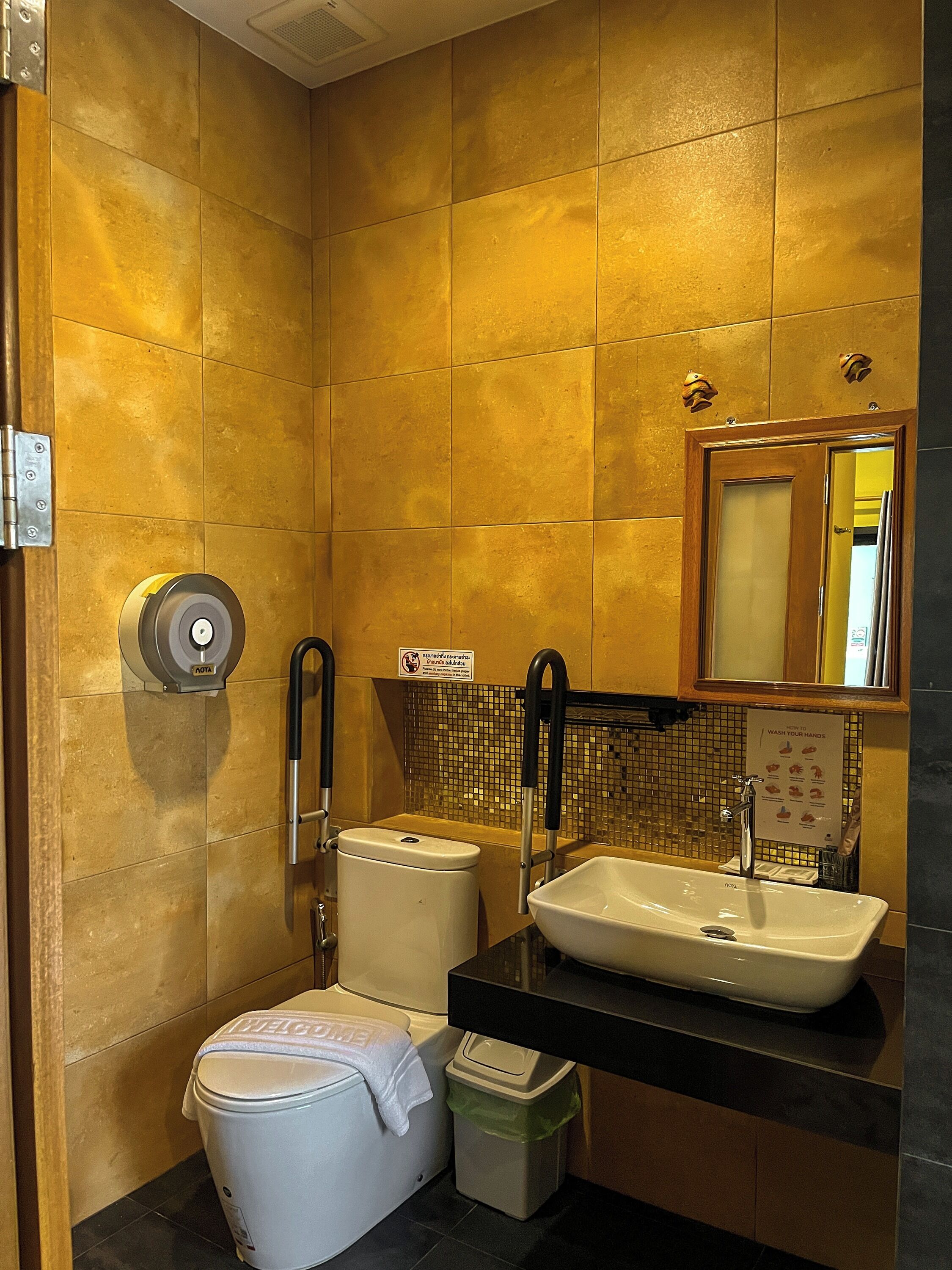 Un baño con inodoro, bidé, lavamanos y espejo.