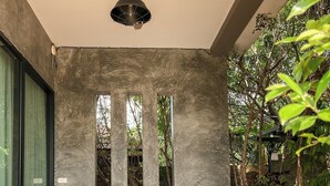 Un espacio exterior moderno con un sofá modular, una mesa metálica con sillas y una lámpara colgante.