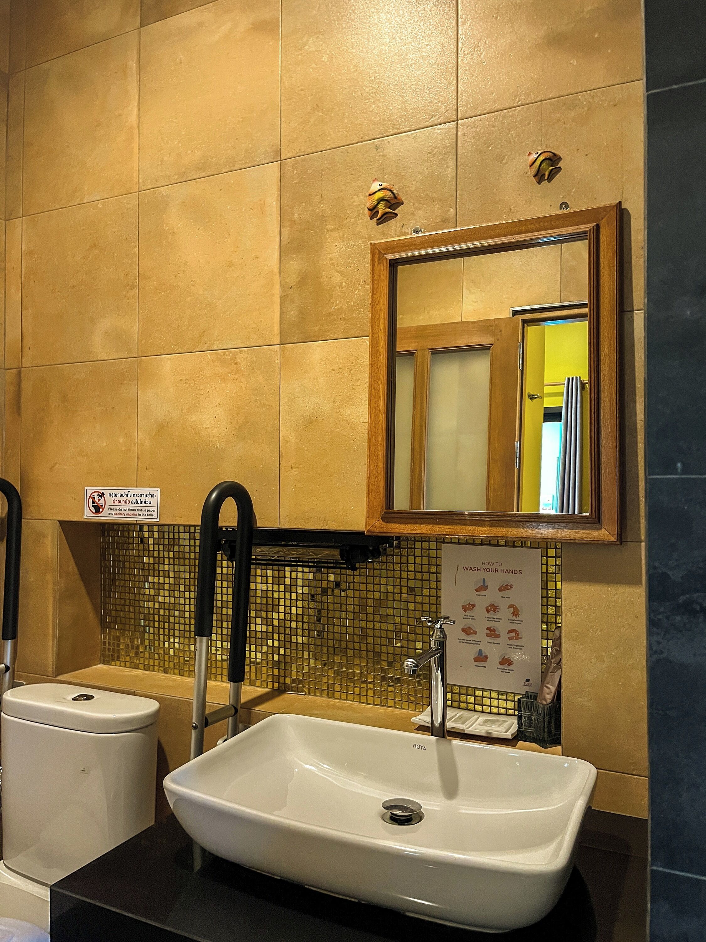 A bathroom with a white sink, a mirror, and a tiled wall.