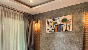 Una habitación de hotel moderna con una cama grande, un cuadro en la pared y una pared decorada con ladrillos.