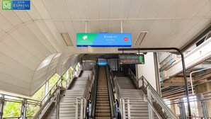 A staircase with a digital sign above, metal railings, and a ceiling with a geometric pattern. - Zayn Express & Suites (Bangkok)