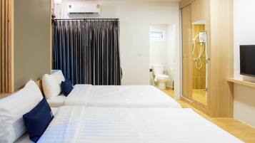 A hotel room with two beds, a shower area, and a television.