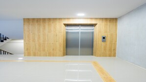 A modern elevator with a metallic finish, surrounded by light-colored walls and a wooden accent wall. - Zayn Express & Suites (Bangkok)