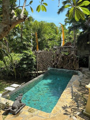 A rectangular swimming pool with clear water, surrounded by stone steps and tropical vegetation. - Nayaka Living Ubud (Ubud)