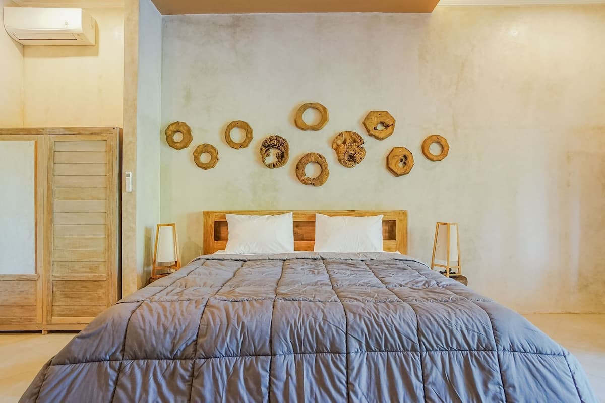 A bedroom with a large bed, wooden headboard, and a wall-mounted circular decoration.