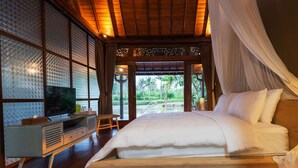 A bedroom with a bed, a television, and a view of the outdoors. - Nayaka Living Ubud (Ubud)