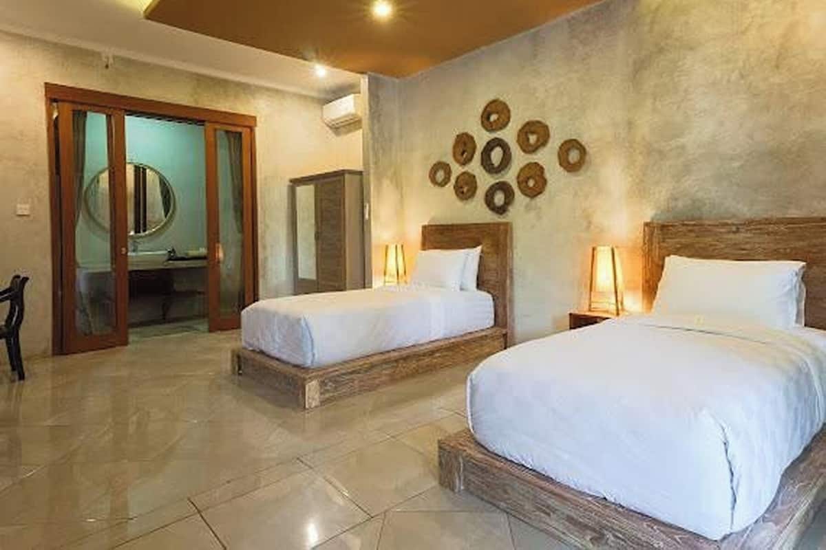 A hotel room with two beds, a wooden headboard, a round mirror, and a wall with circular decorations.