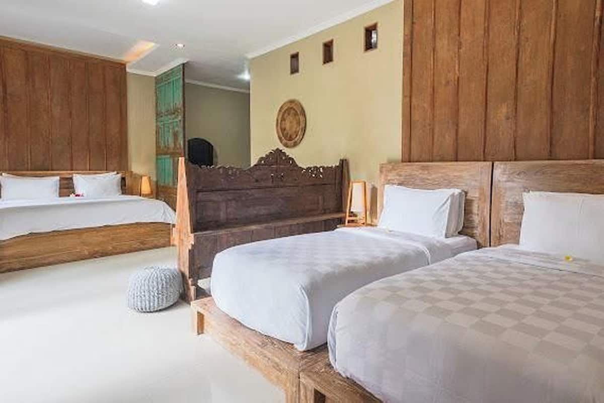 A hotel room with two beds, wooden headboards, and a large mirror on the wall.