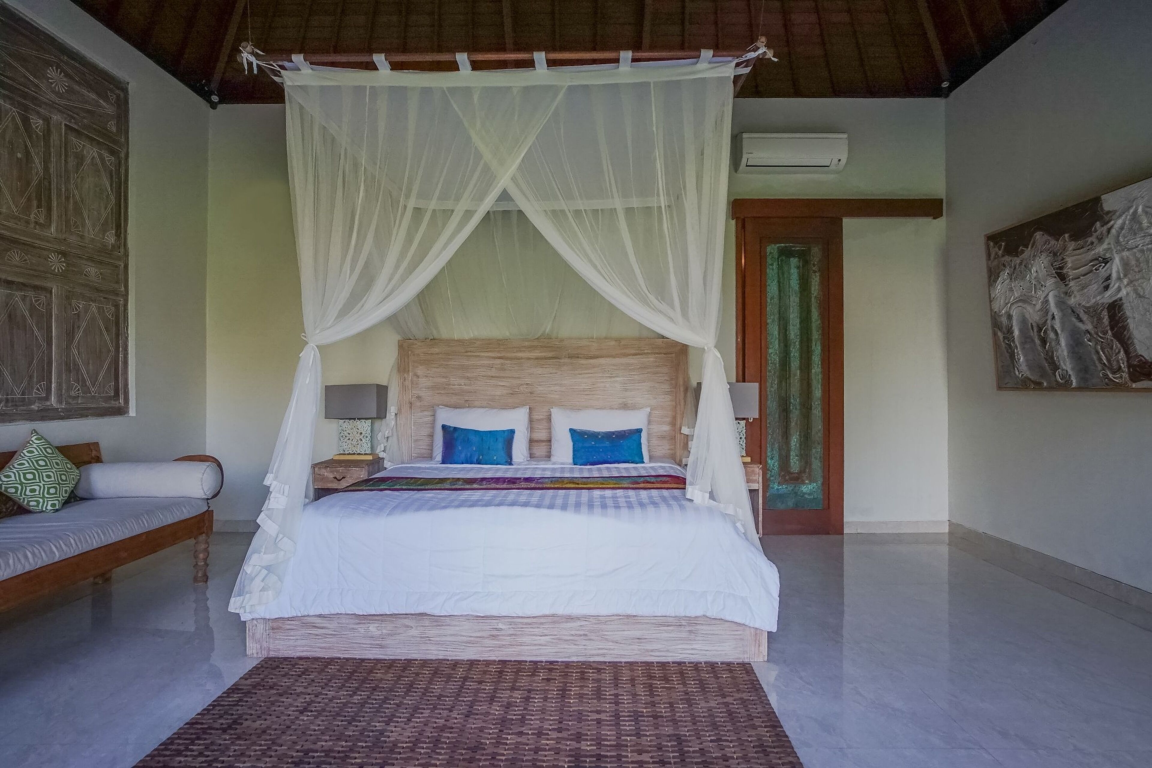 Ein Schlafzimmer mit Bett, weißem Baldachin und einem Holzkopfende.