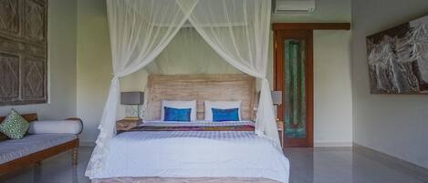 Ein Schlafzimmer mit Bett, weißem Baldachin und einem Holzkopfende.