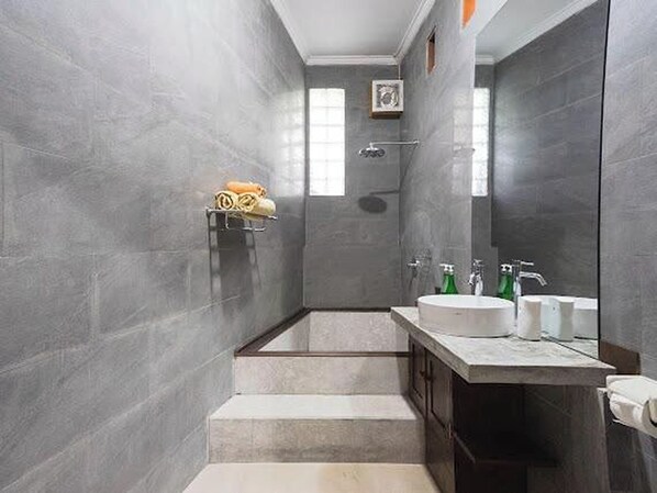 Un baño moderno con paredes de azulejos grises, un lavamanos empotrado y una zona de ducha.