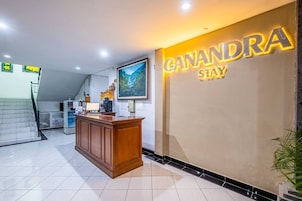 A reception area with a wooden desk, a large framed picture, and a wall sign that reads "CANANDRA STAY".