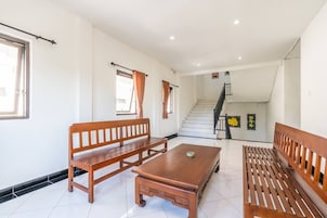 A spacious living area with a wooden bench, a coffee table, and a staircase leading to an upper floor.