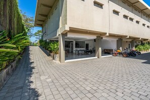 A building with a covered outdoor area, potted plants, and parked motorcycles. - Ganandra Stay Denpasar (Denpasar)