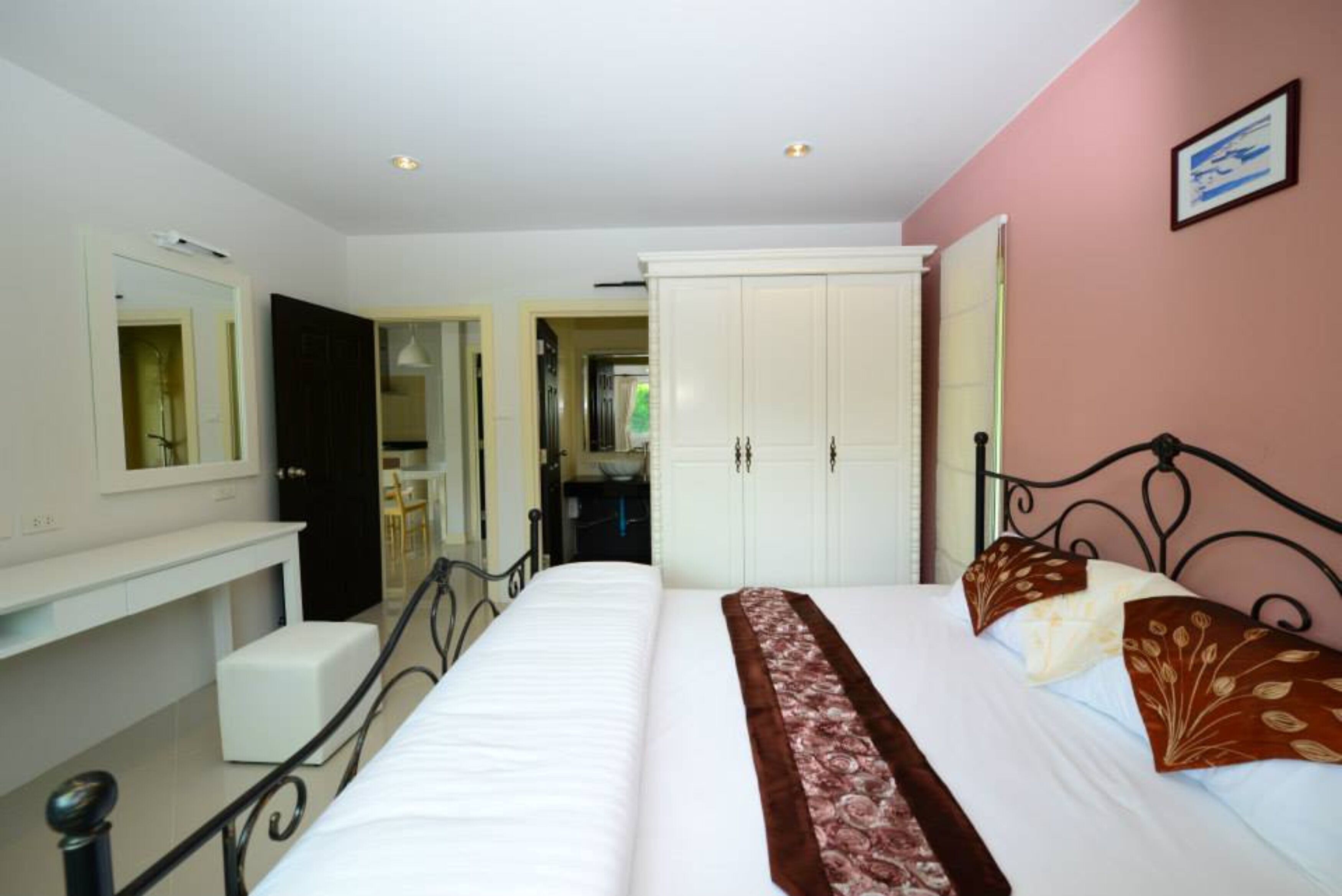 A bedroom with a bed, a wardrobe, a mirror, and a small white bench.