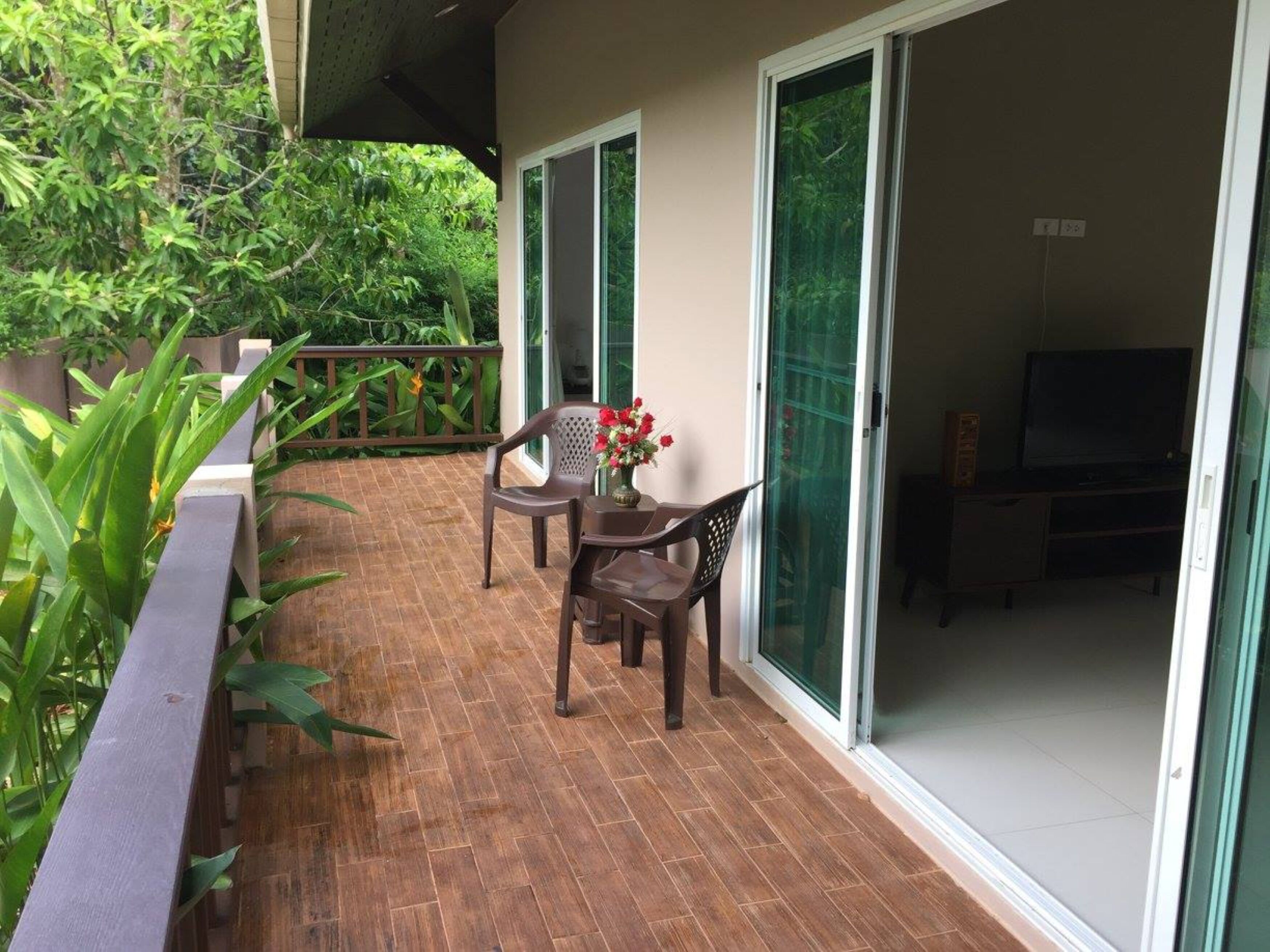 Un patio con una mesa, sillas, un televisor y un cerramiento de vidrio corredizo que da a una habitación.