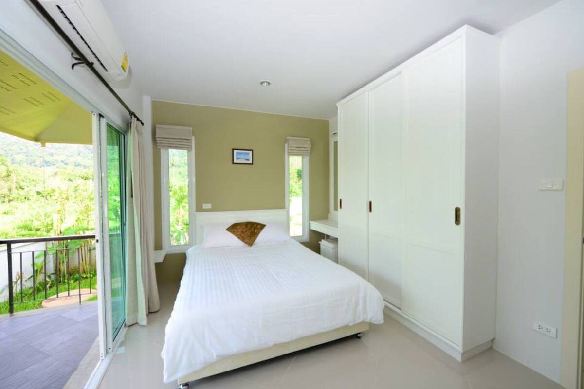 A bedroom with a bed, a wardrobe, and a balcony.