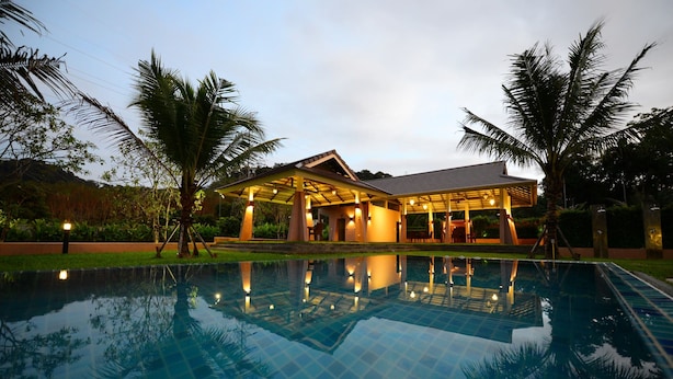 A swimming pool with a house in the background. - Bk Villa (Thep Krasattri)