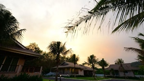 A residential area with houses, palm trees, and a gravel driveway. - Bk Villa (Thep Krasattri)