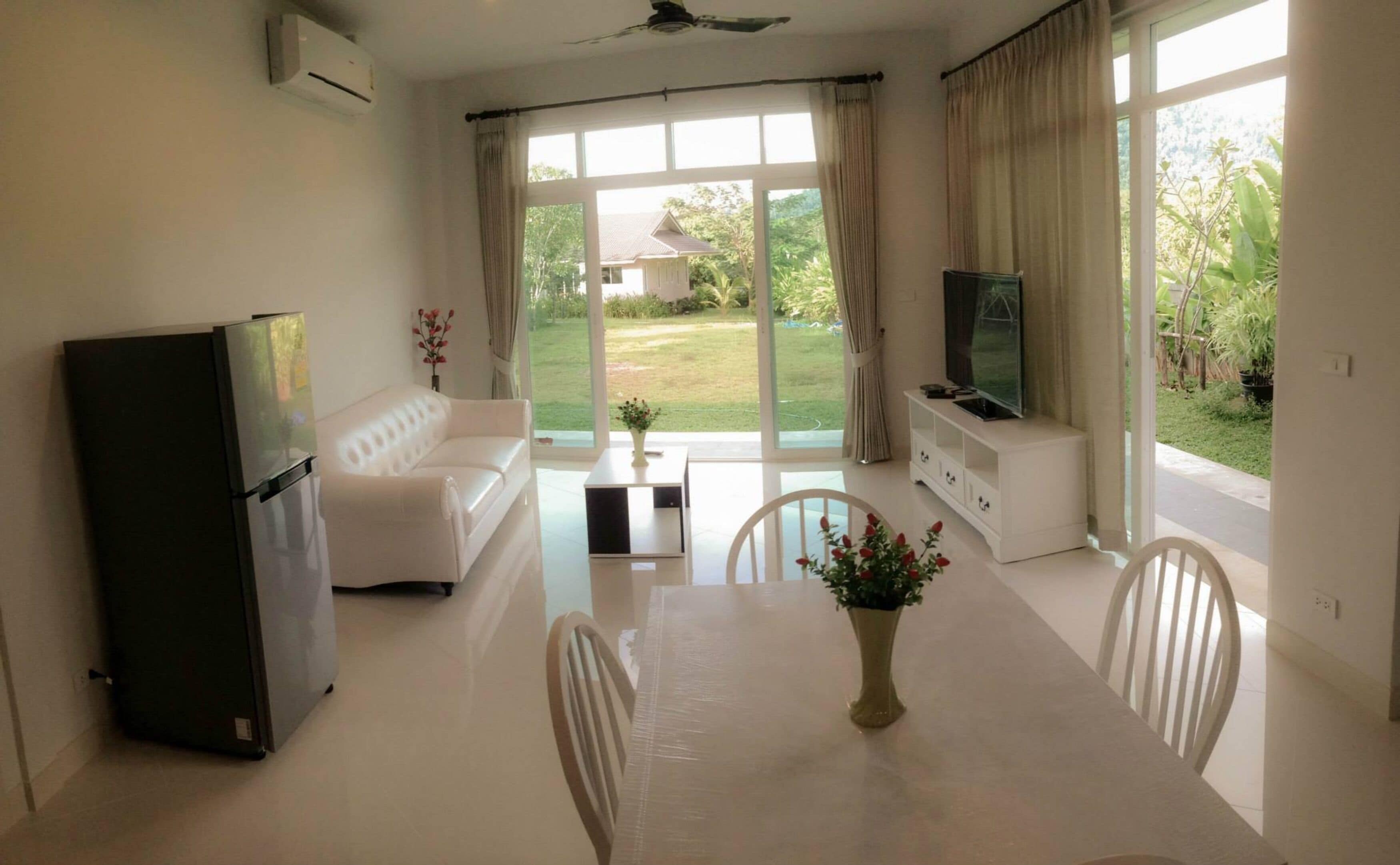 Uma sala de estar moderna com sofá, mesa de jantar e televisão.