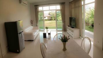 Uma sala de estar moderna com sofá, mesa de jantar e televisão.