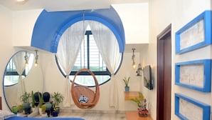 A bedroom with a bed, a hanging chair, a desk, and a window with curtains. - Paradise Homestay Civil Lines, Only Family & Corporate Stays (Nagpur)