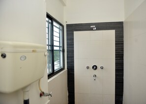 A bathroom with a toilet, a window, and a shower area with a black and white tiled wall. - Paradise Homestay Civil Lines, Only Family & Corporate Stays (Nagpur)
