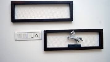 Two wall-mounted picture frames, one empty and one with a horse sculpture, and a white electrical outlet below them.