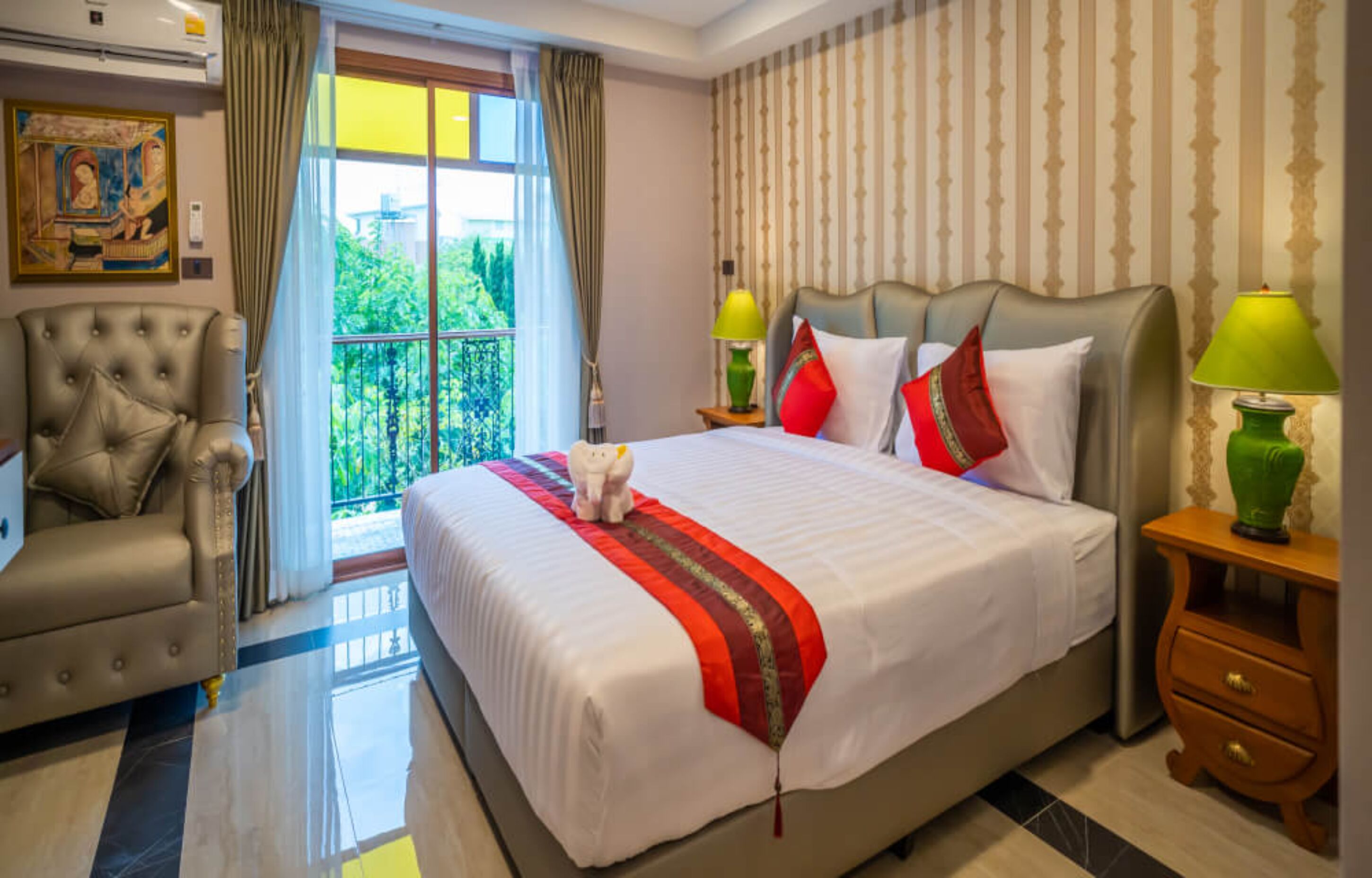 A hotel room with a large bed, a chair, a nightstand, and a view of greenery outside.