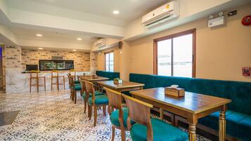 A restaurant with multiple tables and booths, patterned floor tiles, and air conditioning units on the ceiling.