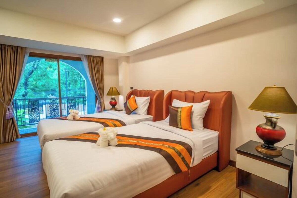 A hotel room with two beds, a balcony, and a nightstand with a lamp.