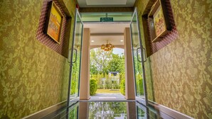 A hallway with patterned wallpaper, glass doors, and a chandelier.
